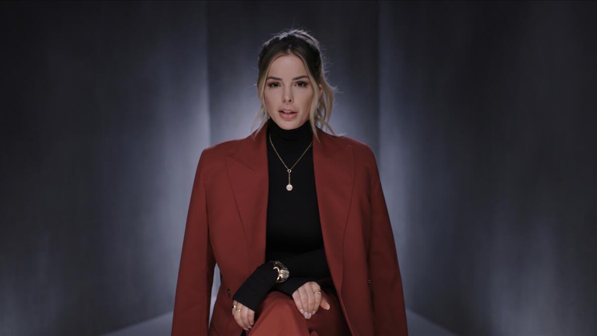 A woman wearing a black turtleneck and burgundy jacket 