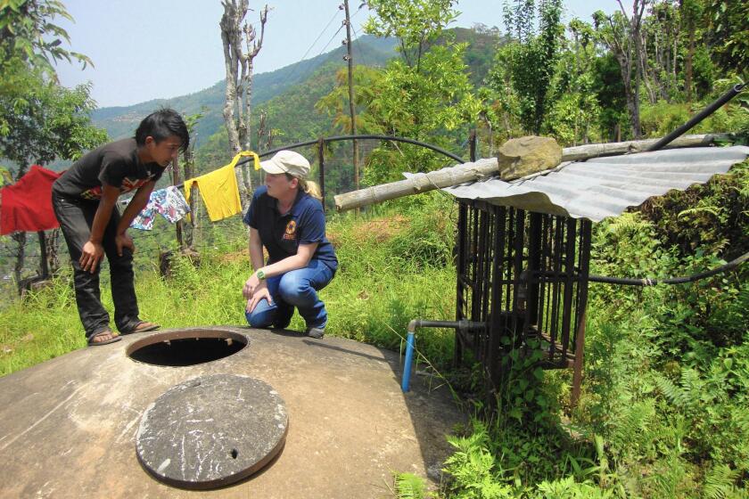 Bikash Ranamayar, 20, a local student, helps Tess Gough, right, a sanitation expert with the Atlanta-based non-profit CARE, inspect a water tank in Paslang, Nepal, about 140 miles west of the capital.