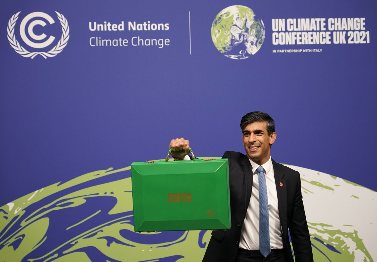 Britain's Chancellor of the Exchequer Rishi Sunak holds up a Green briefcase as he arrives for a speech at the COP26 U.N. Climate Summit in Glasgow, Scotland, Wednesday, Nov. 3, 2021. The British government plans to make the U.K. "the world's first net-zero aligned financial center" as companies and investors seek to profit from the drive to build a low-carbon economy. Sunak will lay out the government's plans during a speech Wednesday as top financial officials from around the world meet at the U.N. climate conference in Glasgow, Scotland. (AP Photo/Alberto Pezzali)