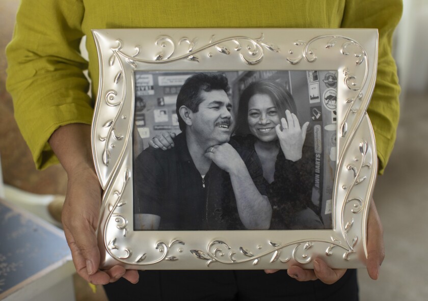 A woman holds a framed, black-and-white photo of herself and her husband.