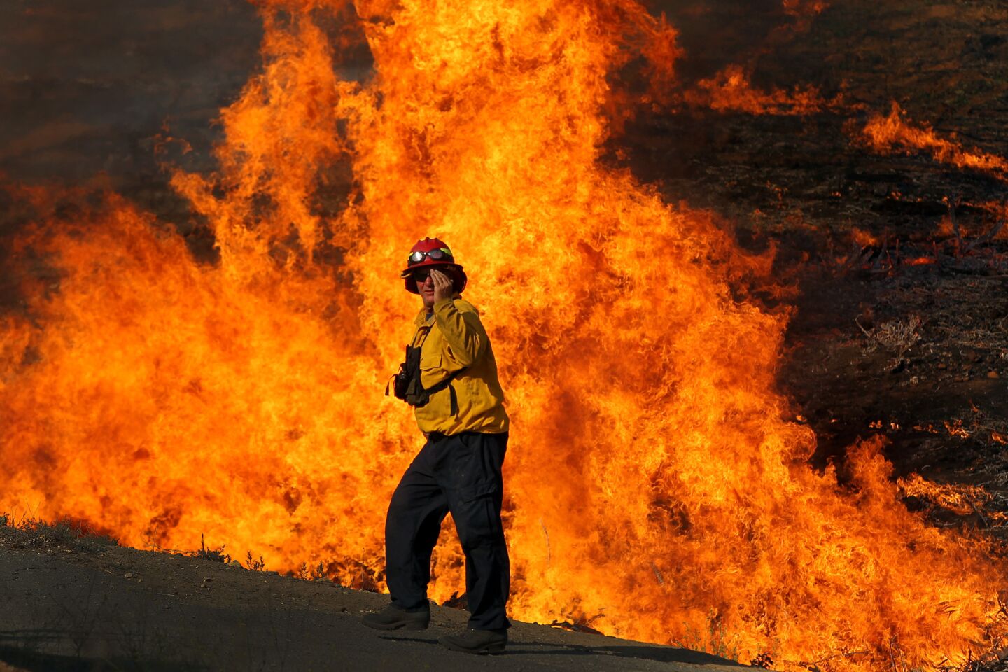 A firefighter walks near a blaze in San Marcos.