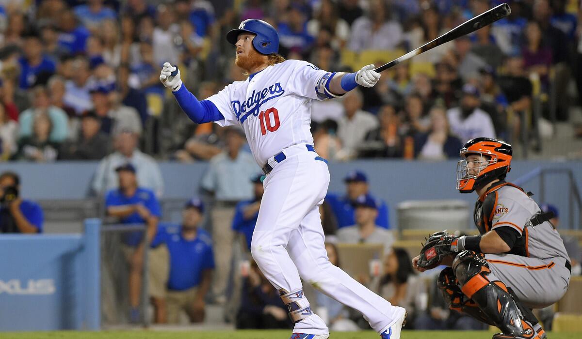 Dodgers' Justin Turner follows through on a solo home run as San Francisco Giants catcher Buster Posey watches during the fourth inning on Wednesday.