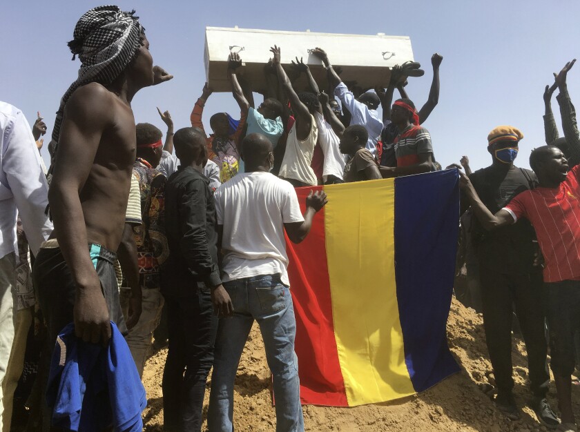 Mourners chanting as some hold the coffin during the funeral of one of the victims who was killed earlier this week, at a cemetery in N'Djamena, Chad, Saturday, May 1, 2021. Hundreds of chanting mourners carrying Chadian flags gathered Saturday to bury victims who were shot dead earlier this week amid demonstrations against the country's new military government.(AP Photo/Sunday Alamba)