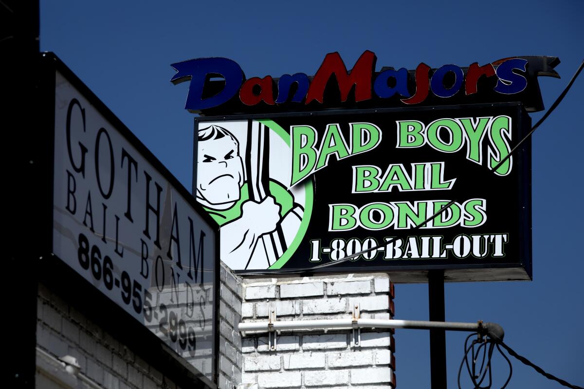A sign for Bad Boys Bail Bonds atop a building, near another sign that says Gotham Bail Bonds