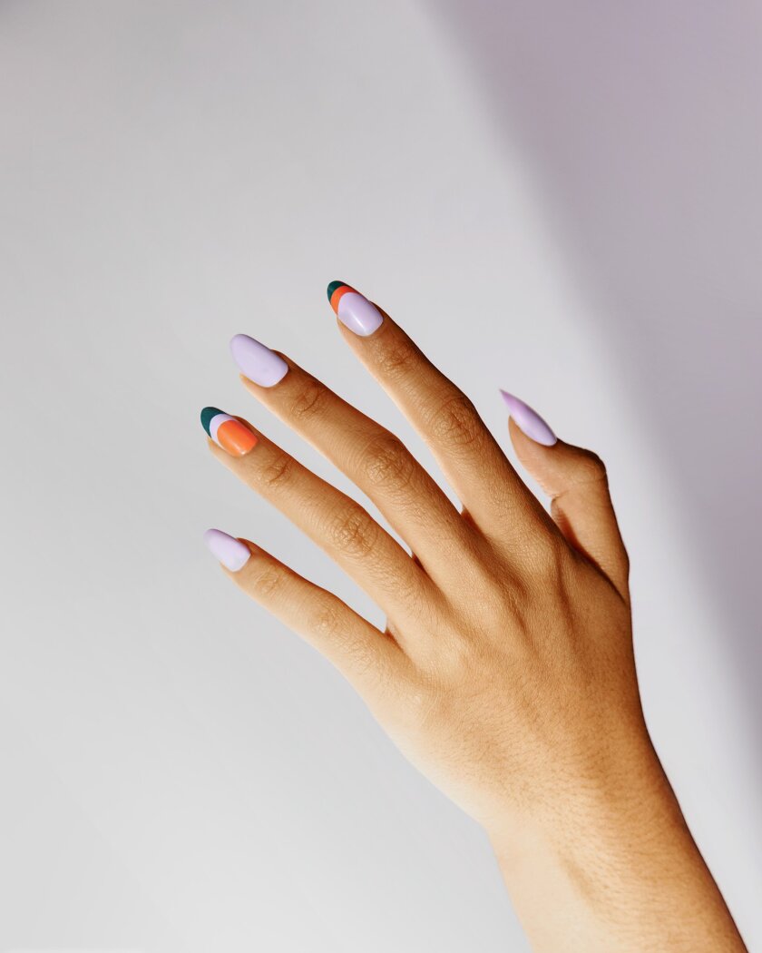 Poketo nail polish shown on a hand in lilac, green and orange