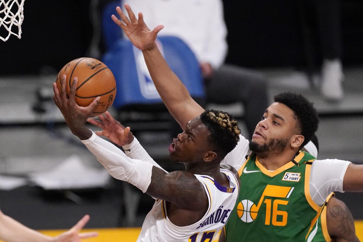 El base de Los Lakers de Los Ángeles Dennis Schroder lanza el balón mientras lo defiende Juwan Morgan del Jazz