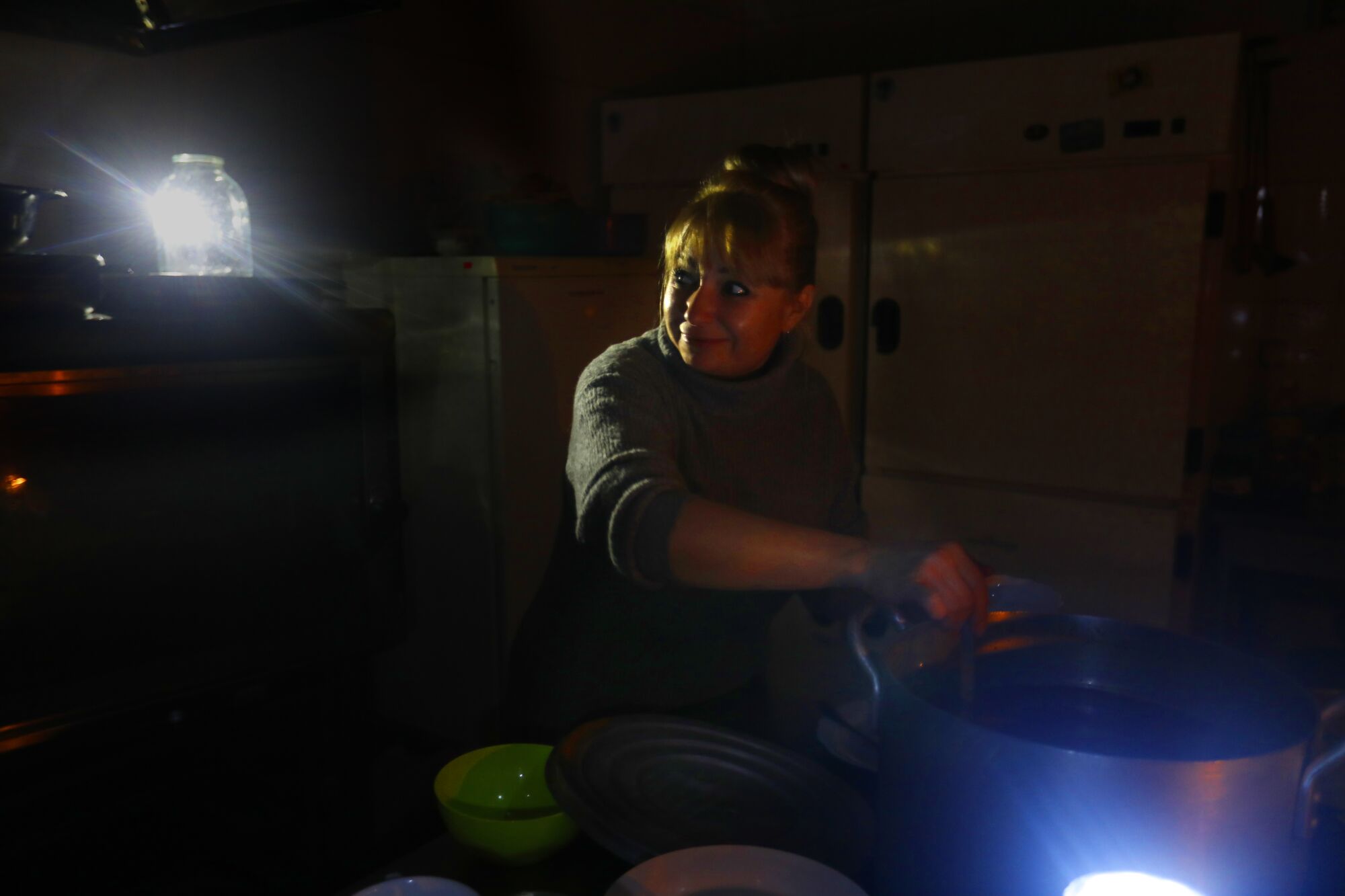 Une femme cuisine à la chandelle.  