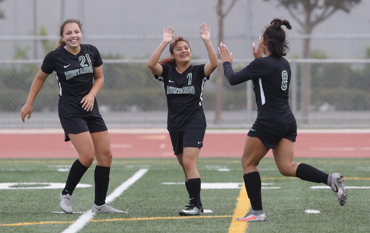 Costa Mesa teammate Jade Young (21), Carolina Osorio (7) and Jevaughn Burns (8) celebrate a goal in Thursday's game.