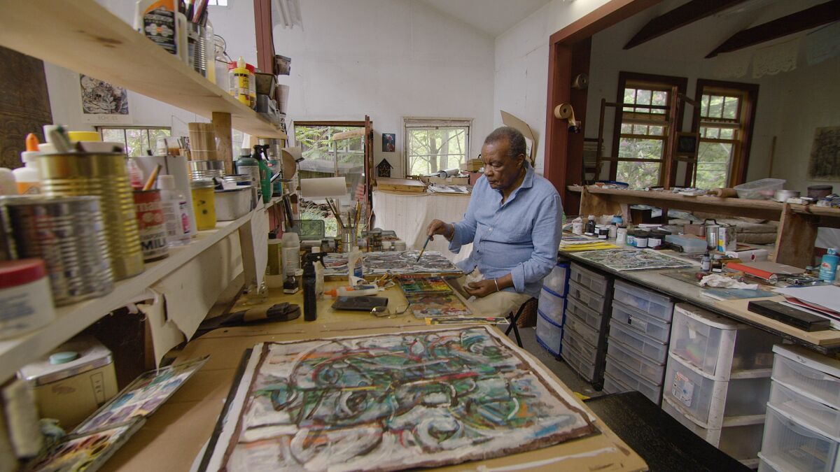 Artist and curator David C. Driskell is seen working on paintings in his studio