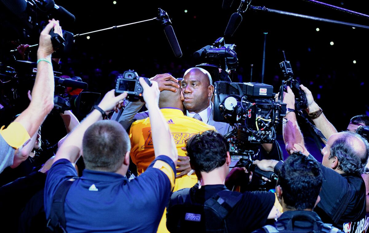 Surrounded by cameras Kobe Bryant and Magic Johnson embrace before Bryant's final game at the Staples Center Wednesday.