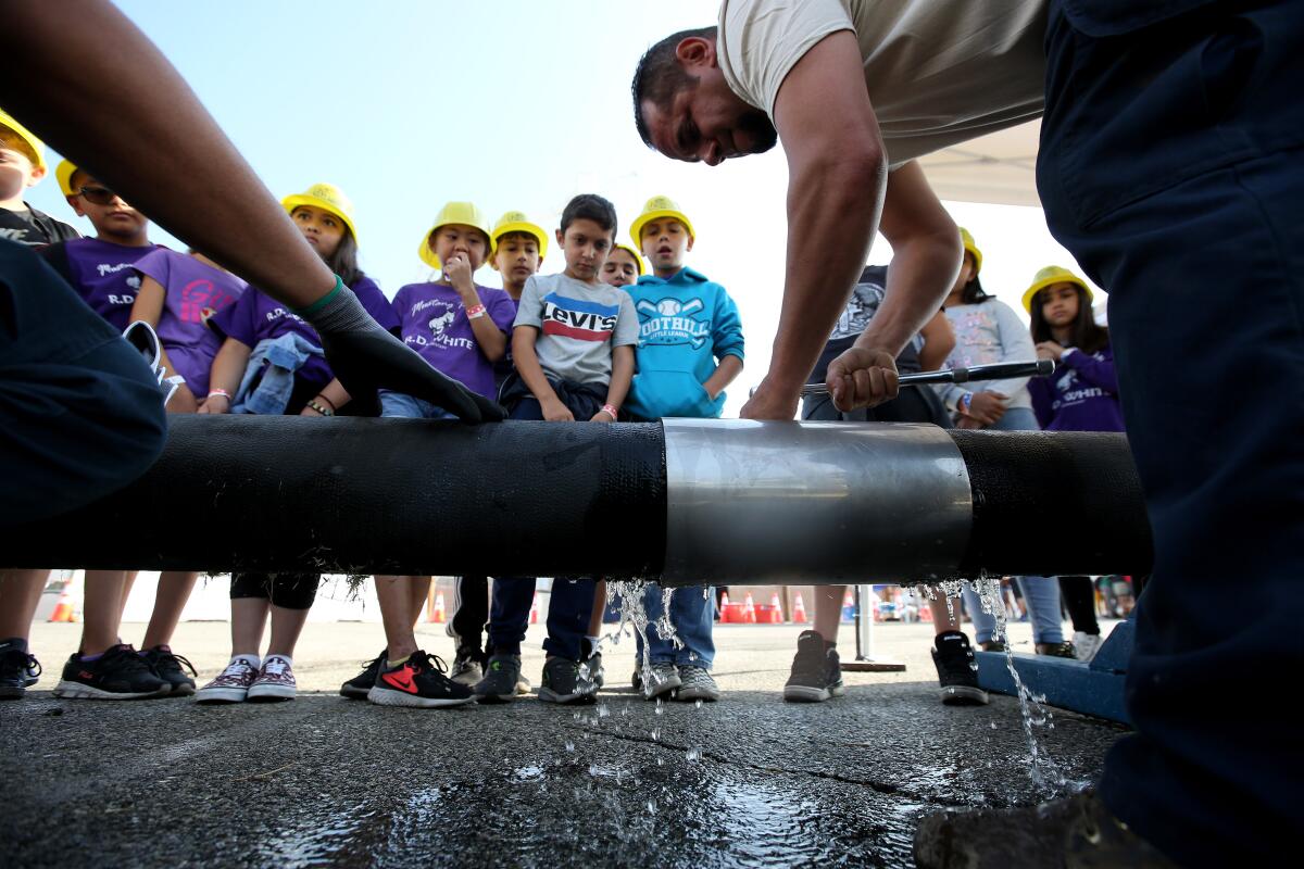 Students from R. D. White Elementary School learn how senior water systems mechanic Chris Ercek repairs broken water mains at the annual Glendale Water & Power Utility Day at the utility operations center in Glendale on Thursday.