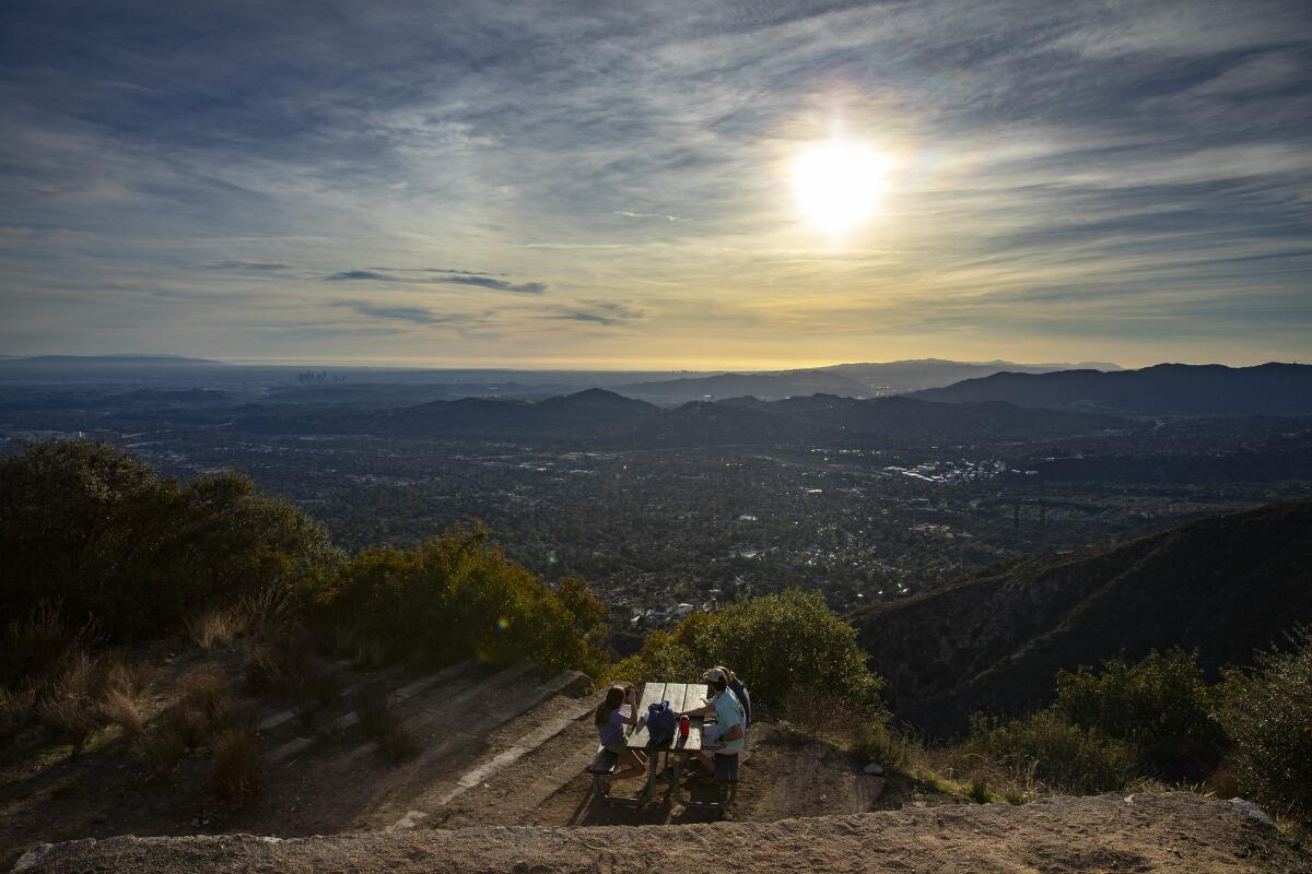 Hikers take in the views from a picnic bench atop Echo Mountain in Altadena.