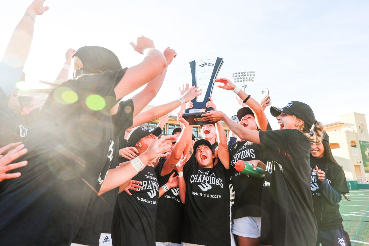 Forward Alex Jaquez lifts the Big West tournament trophy as she celebrates with teammates.