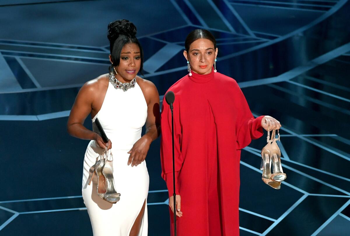 Tiffany Haddish, left, and Maya Rudolph onstage with their shoes at the 90th Academy Awards.