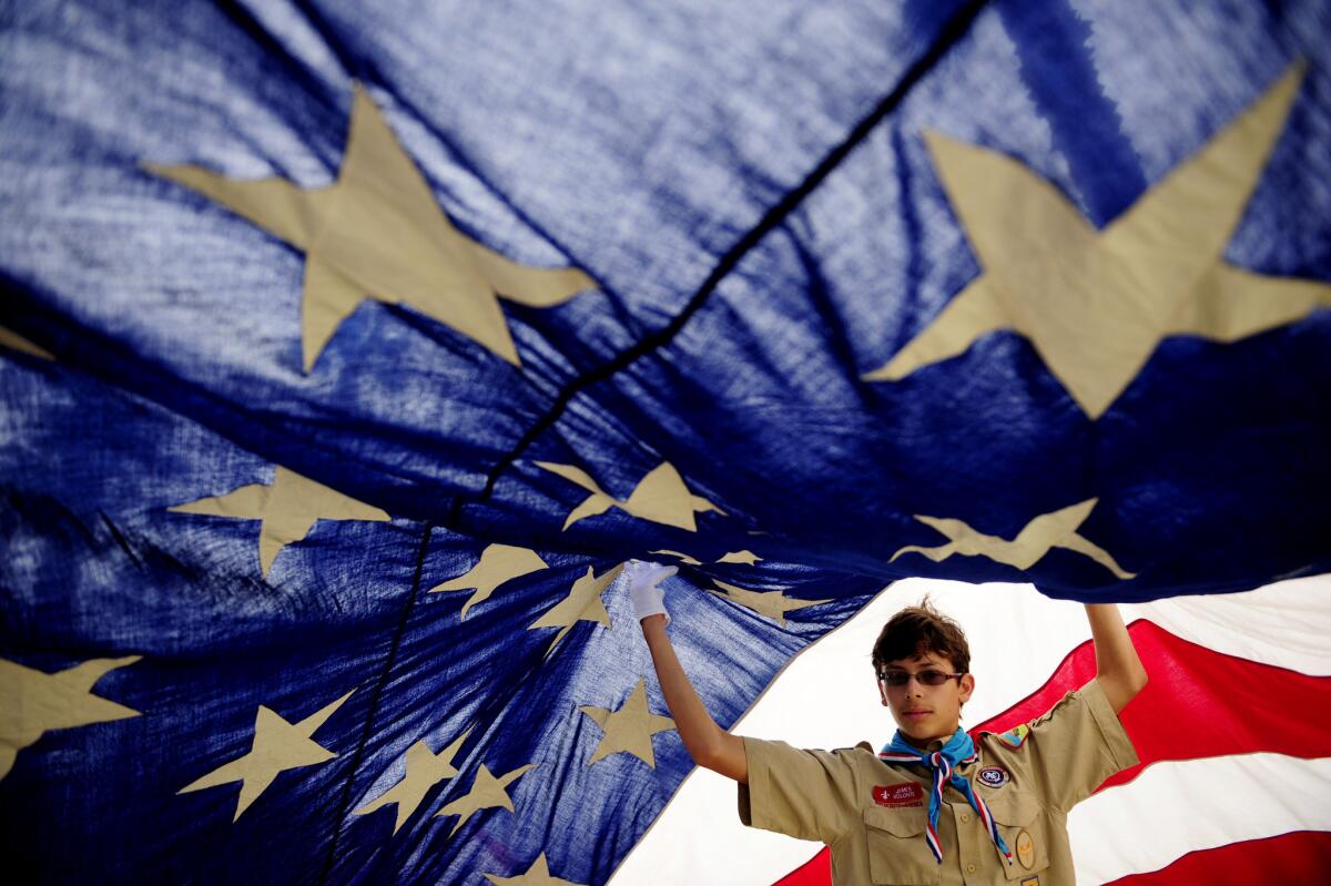 Boy Scout James Volonte, then 14, helps raise an American flag before the start of the annual July 4 parade in Huntington Beach in 2013.