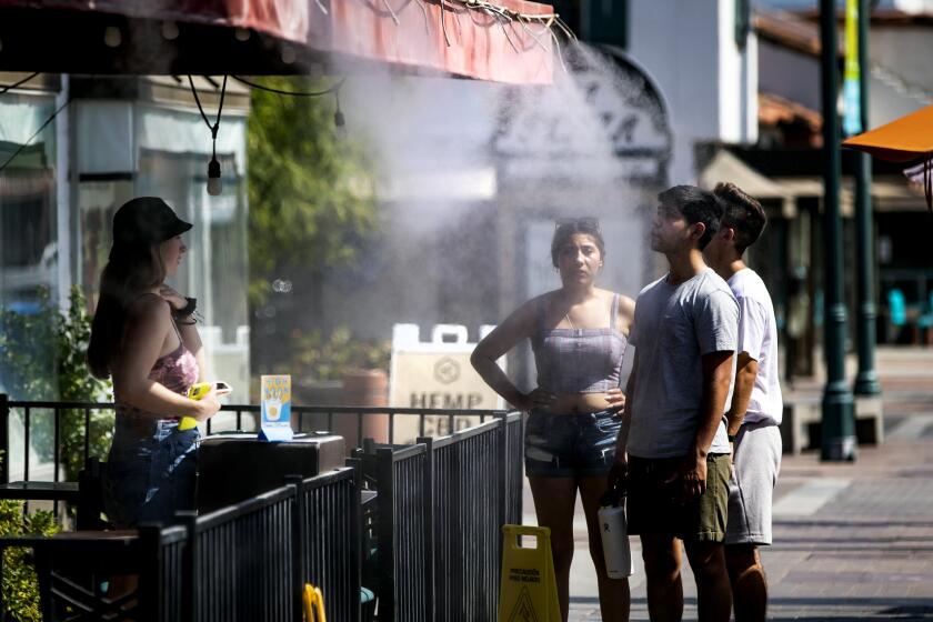 PALM SPRINGS, CA - JULY 8, 2021: Customers cool off at a downtown restaurant mister in 110 degree temperatures on July 8, 2021 in Palm Springs, California. Another heat wave is expected this weekend in Southern California.(Gina Ferazzi / Los Angeles Times)