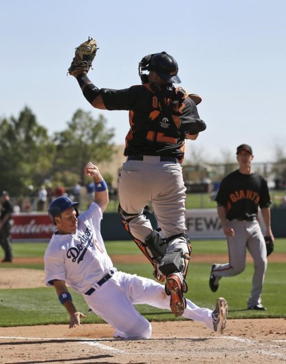 Mark Ellis scores on a double by Jeremy Moore as San Francisco Giants catcher Guillermo Quiroz catches a high throw during the second inning of an exhibition spring training baseball game on Tuesday, Feb. 26, 2013 in Glendale.