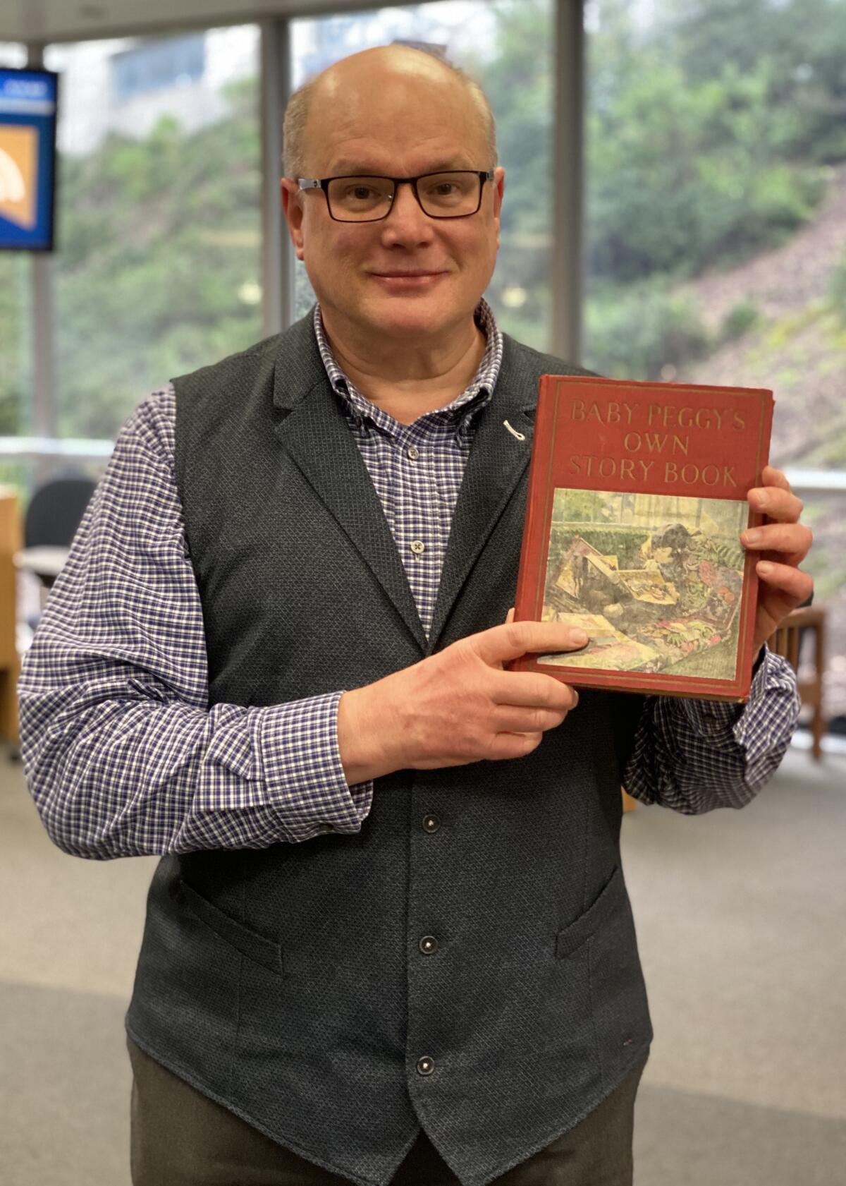 UCSD Geisel Library events and exhibits coordinator Scott Paulson holds one of his treasured Baby Peggy books.