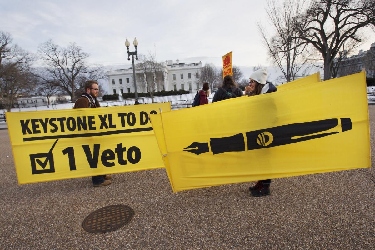 Activists Danny Ruthenberg-Marshall, left, and Lindsey Halvorson carry signs outside the White House after attending a rally in support of President Obama's veto of the Keystone XL pipeline legislation.