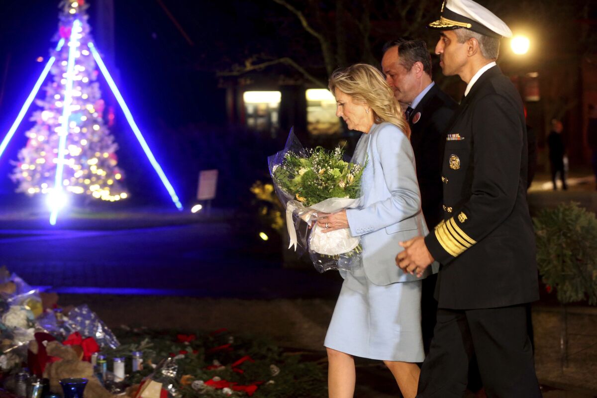 First lady Jill Biden, center, second gentleman Douglas Emhoff, left and U.S. Surgeon General Dr. Vivek Murthy, right, pay their respect at the Waukesha Christmas Parade memorial at Veterans Park in Waukesha, Wis., on Wednesday, Dec. 15, 2021. (Angela Peterson/Milwaukee Journal-Sentinel via AP)