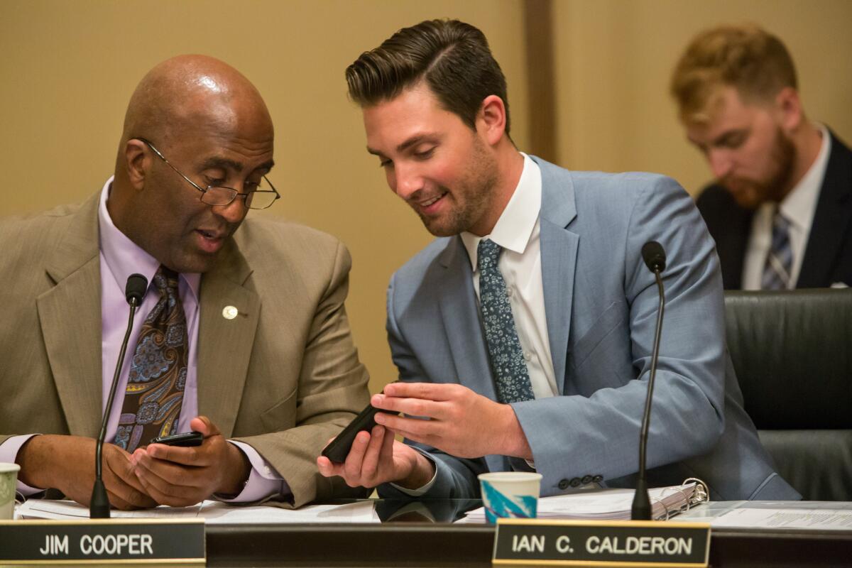 Assemblyman Jim Cooper, left, checks out Assemblyman Ian C. Calderon's cellphone during a hearing session at the Capitol on July 7, 2015.