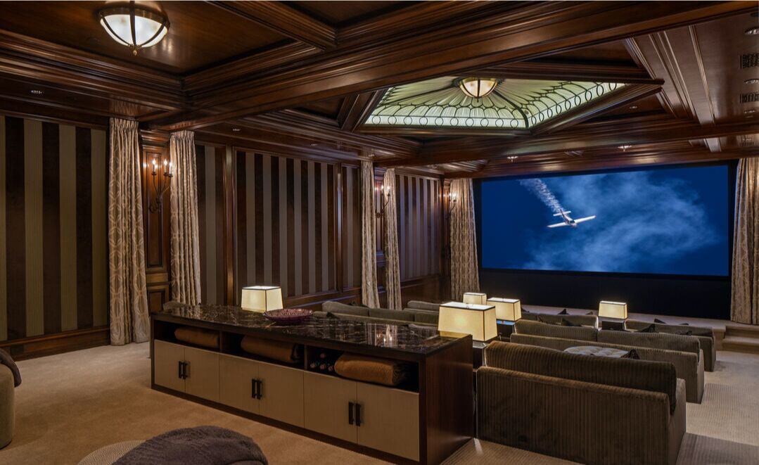 The theater with a large flat screen and movie theater seating.