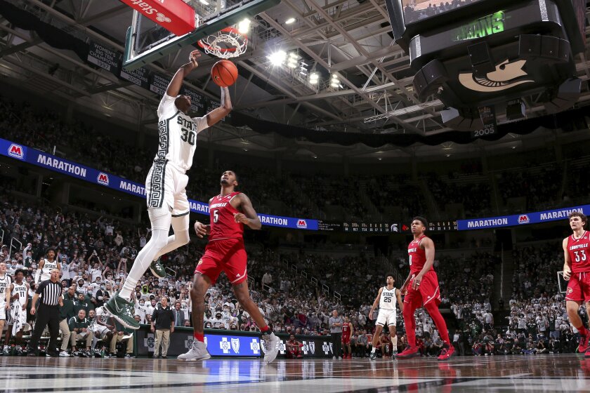 Michigan State's Marcus Bingham Jr., left, dunks against Louisville's Malik Williams (5) as Noah Locke (0) and Matt Cross (33) and Michigan State's Malik Hall (25) watch during the second half of an NCAA college basketball game, Wednesday, Dec. 1, 2021, in East Lansing, Mich. (AP Photo/Al Goldis)