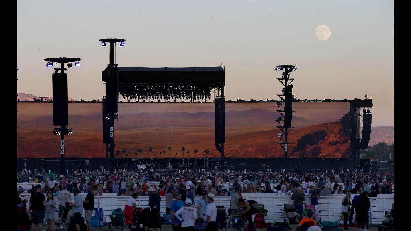 The moon looms over the stage as fans wait for Bob Dylan to perform.