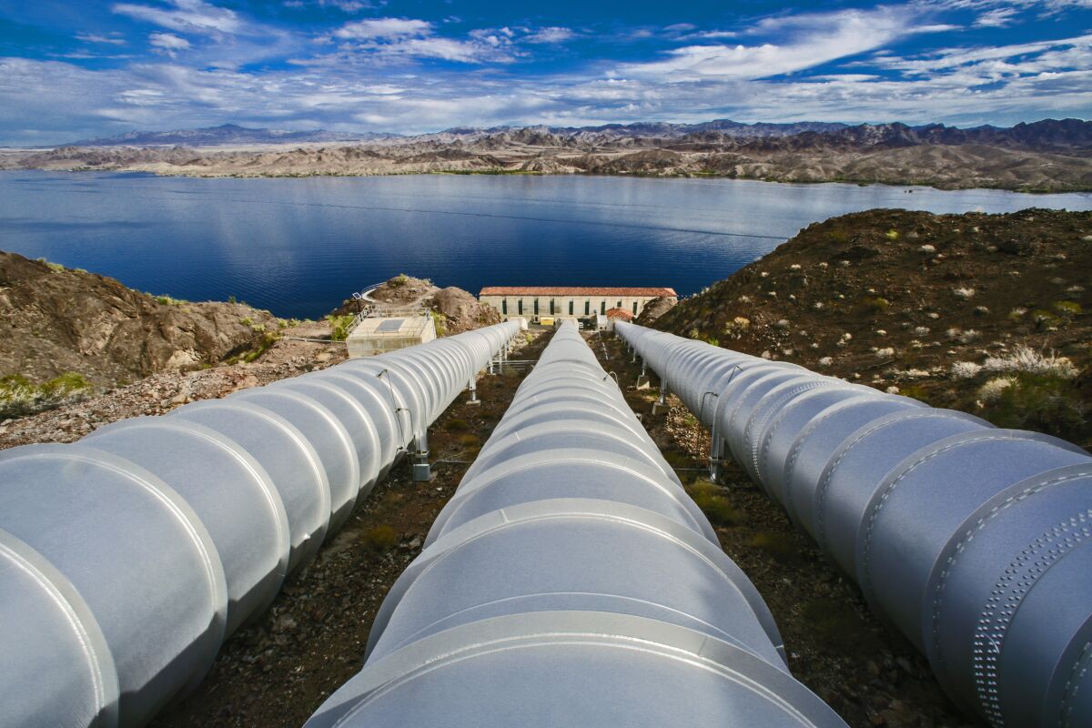 Pipelines run down to a water pumping plant near a river