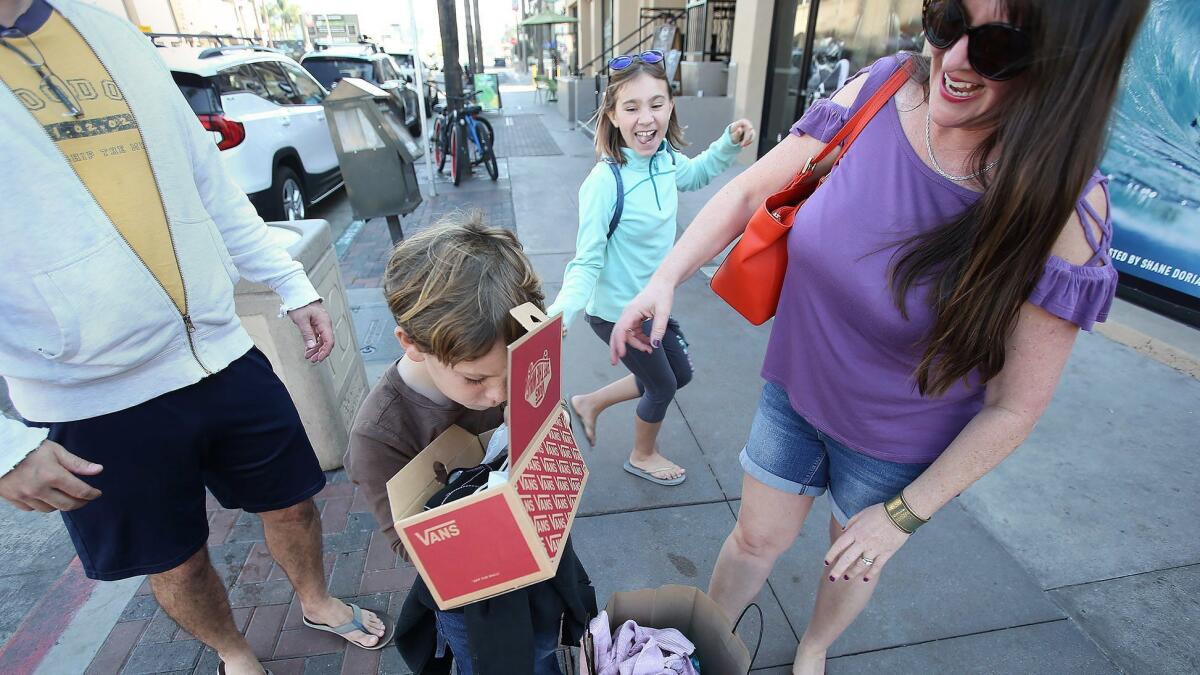 Emerson Peralta peeks at the new Vans shoes he got Friday in downtown Huntington Beach with his family.