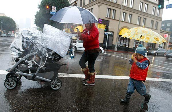 As the rain comes down, Sebastian Hernandez, 3, and his mother, Estela, cross Wilshire Boulevard in Los Angeles. They were on their way to the drugstore.