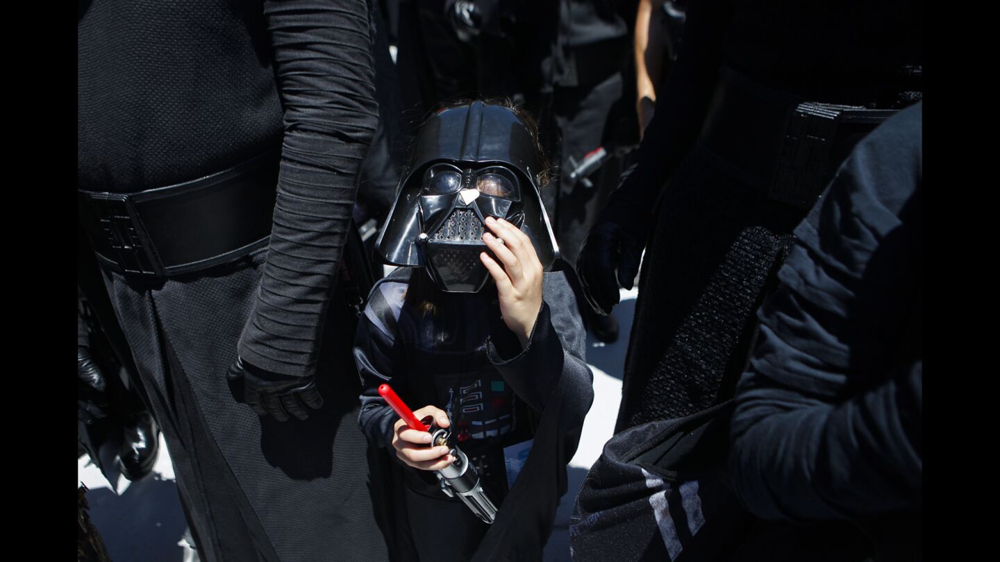Elizabeth Sutra, 8, of San Diego fixes her Darth Vader helmet during the second day of Comic-Con.
