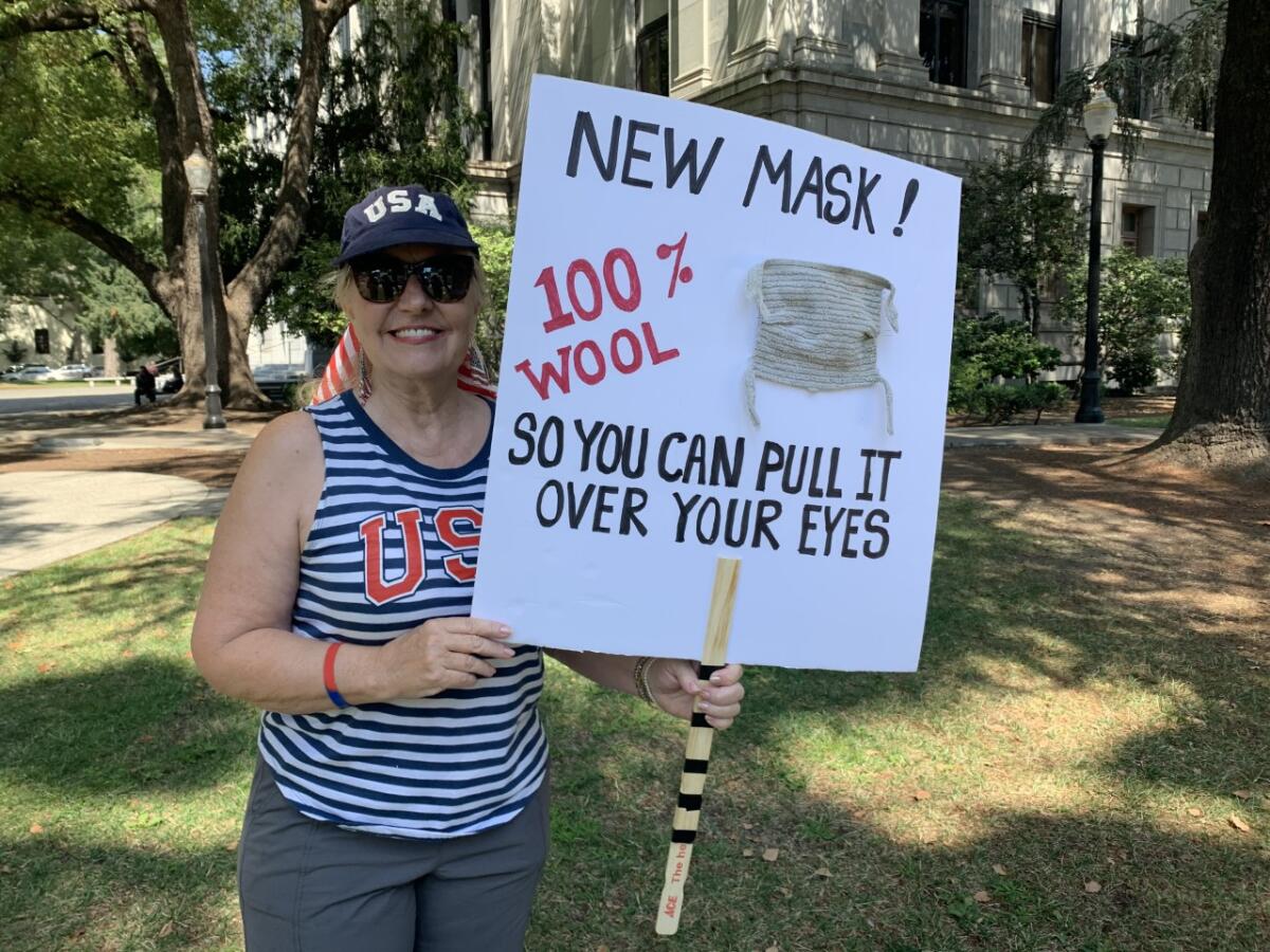 Donna Hogue of Granite Bay holds a sign expressing on her views on face masks at the "United We Stand" rally in Sacramento.