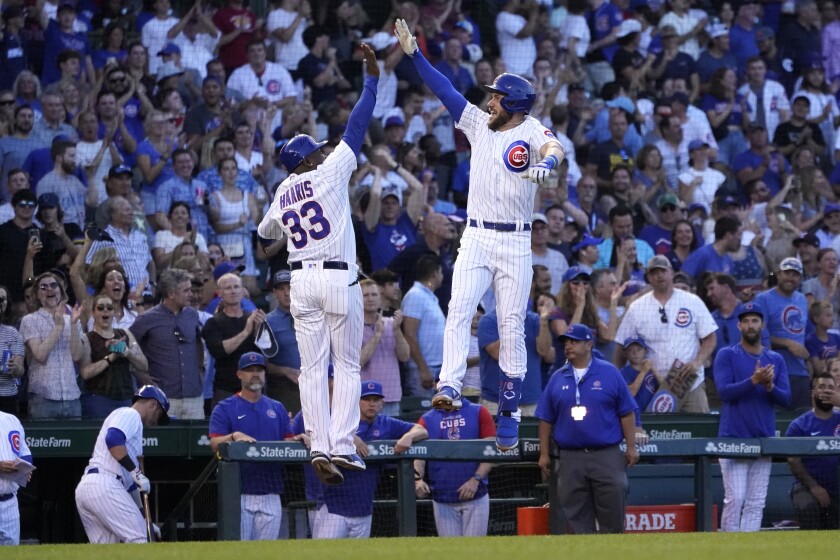 Chicago Cubs' Patrick Wisdom, right, celebrates his grand slam against the Cincinnati Reds with third base coach Willie Harris during the second inning of a baseball game Thursday, June 30, 2022, in Chicago. (AP Photo/Charles Rex Arbogast)
