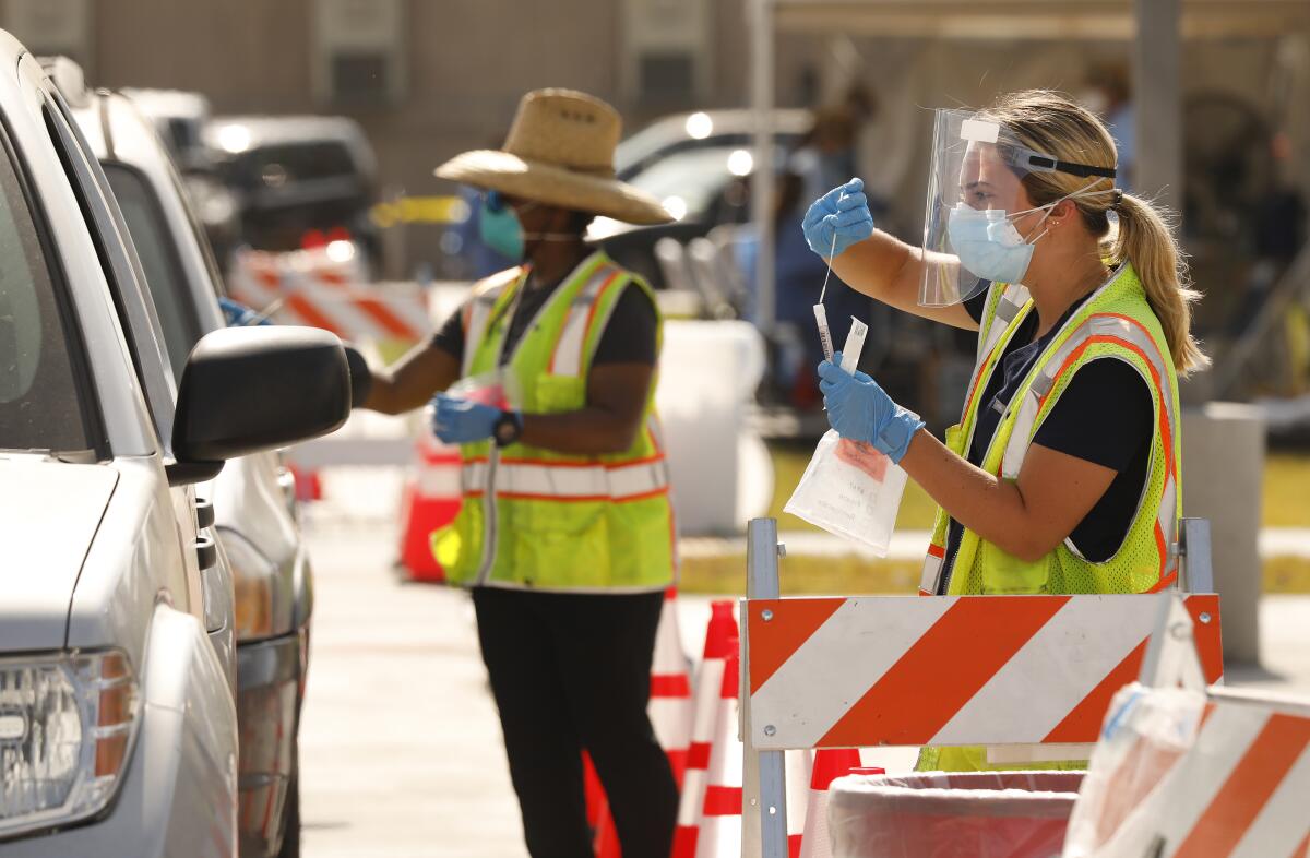 Hannah Mikus, right, demonstrates how to self-administer a coronavirus test to a driver on July 8 in South Los Angeles.