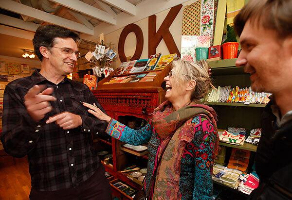 Arno Hesse, left, and Guillame Lebleu, right, residents of San Francisco's Bernal Heights neighborhood, visit with Darcy Lee, owner of Heartfelt, a store that sells craft items. Hesse and Lebleu came up with the idea of a credit card called Bernal Bucks, a "complementary currency" that allows shoppers to earn credits and give back to the tight-knit community.