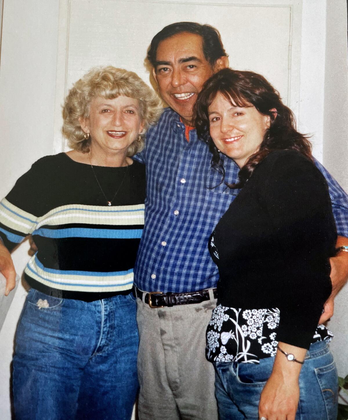 Jesse Macias with his arms around two women, one on either side of him