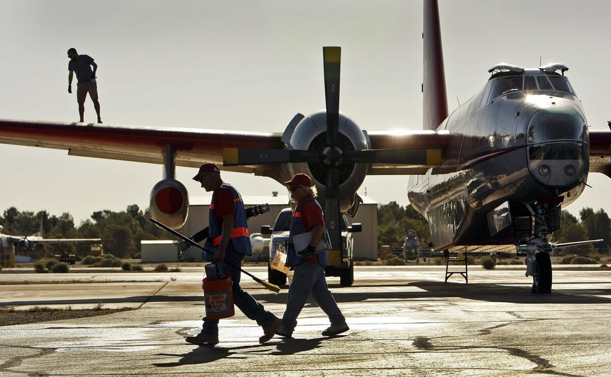 Tom Dux, a pilot with Neptune Aviation Services Inc. of Missoula, Mont., walks on the wing of his Lockheed P-2V tanker No. 7 in a preflight check as the wildfire tankers stage at General William J. Fox Airfield in Lancaster. The Neptune Aviation Services planes were called in to battle the Powerhouse fire that swept into the Angeles National Forest in the Lake Hughes and Lake Elizabeth area.