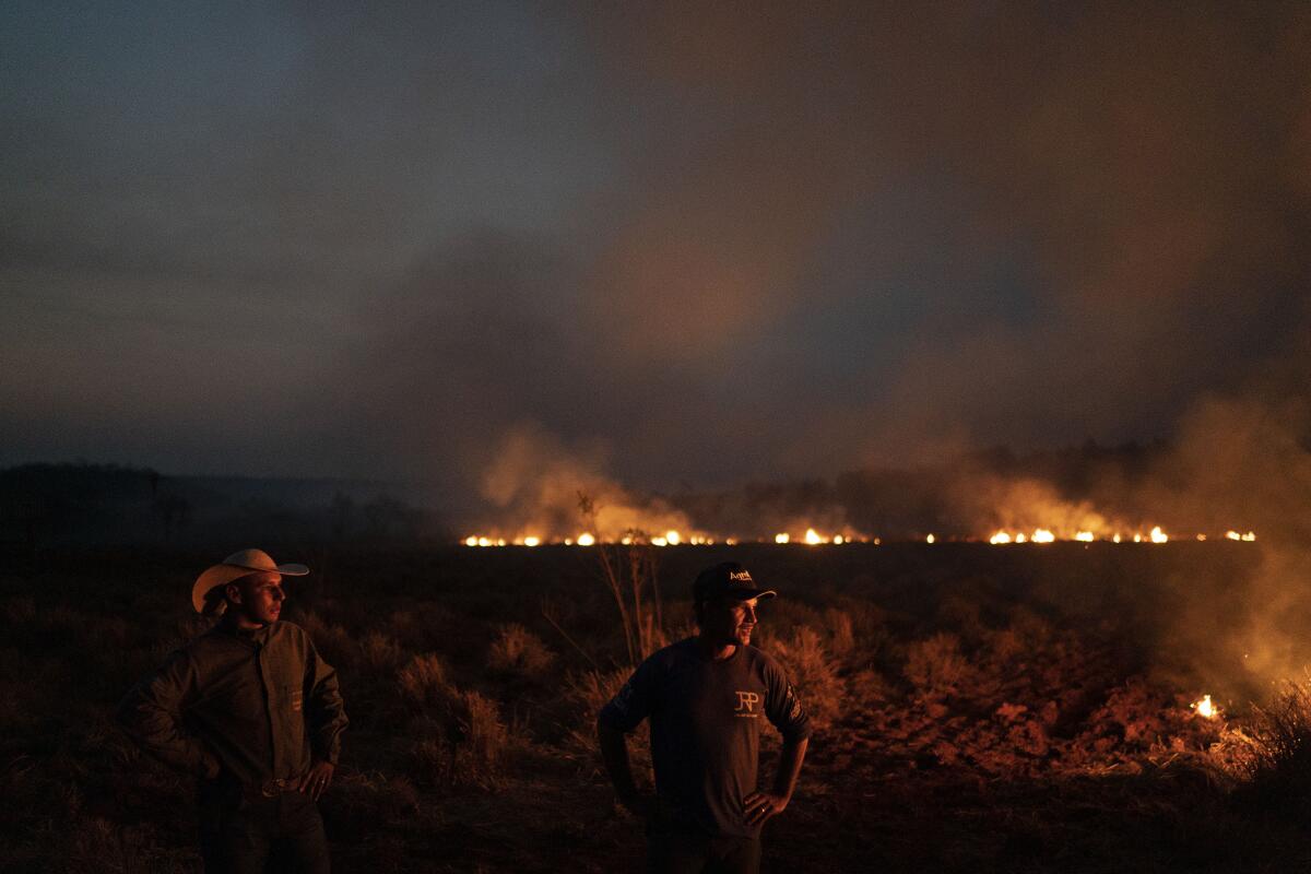 Neri dos Santos Silva, center, watches an encroaching fire threat after digging trenches to keep the flames from spreading to the farm he works on, in the Nova Santa Helena municipality, in the state of Mato Grosso, Brazil, Friday, Aug. 23, 2019. Under increasing international pressure to contain fires sweeping parts of the Amazon, Brazilian President Jair Bolsonaro on Friday authorized use of the military to battle the massive blazes. (AP Photo/Leo Correa)