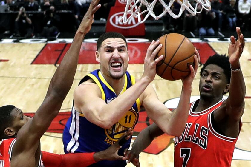 Golden State Warriors' Klay Thompson (11) shoots between Chicago Bulls' Kris Dunn (32) and Justin Holiday, right, during the second half of an NBA basketball game Wednesday, Jan. 17, 2018, in Chicago. The Warriors won 119-112. (AP Photo/Charles Rex Arbogast)