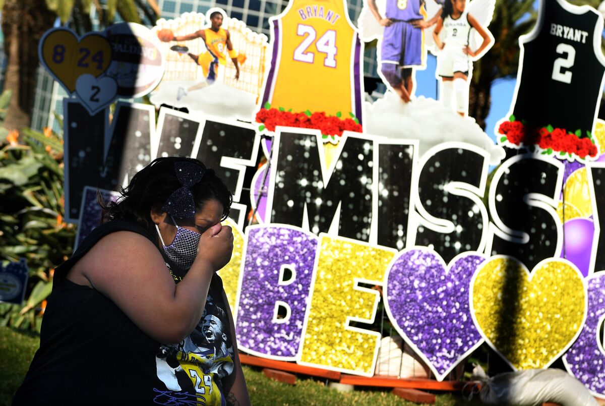 A woman cries in front of a Kobe Bryant mural outside Staples Center.
