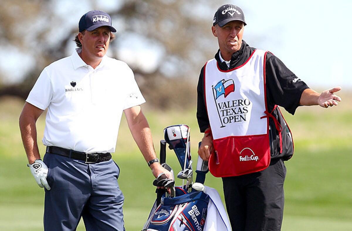 Phil Mickelson and caddie Jim Mackay discuss a shot during the third round of the Valero Texas Open at TPC San Antonio.