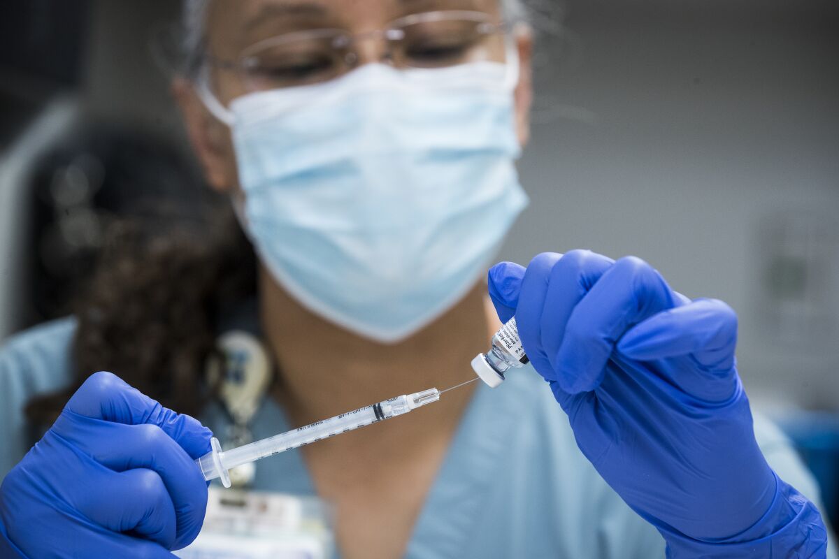 Pharmacy technician Sochi Evans fills a syringe with a Pfizer-BioNTech COVID-19 vaccine.
