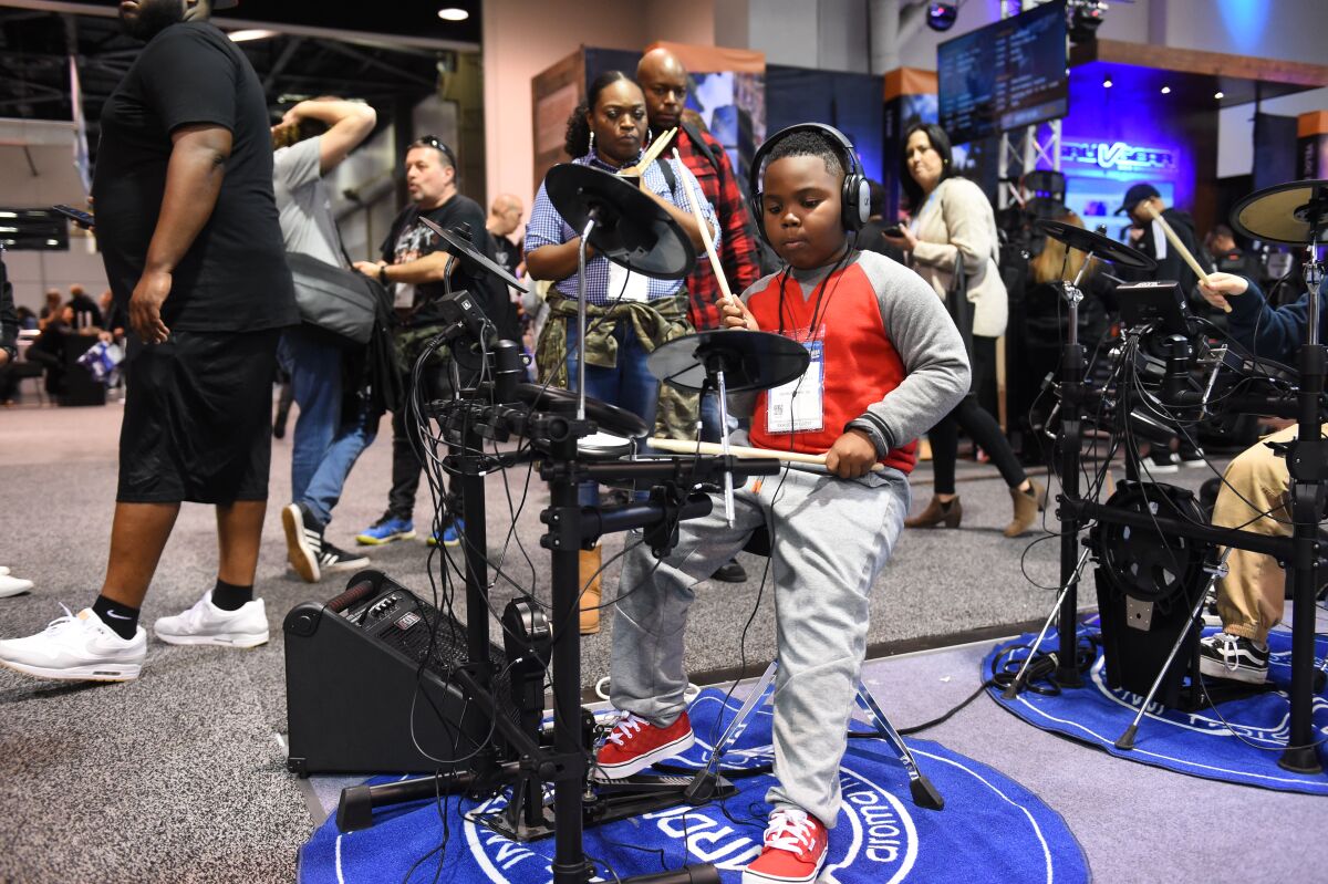 A young attendee plays on an Aroma electronic drum kit at the 2019 NAMM Show 