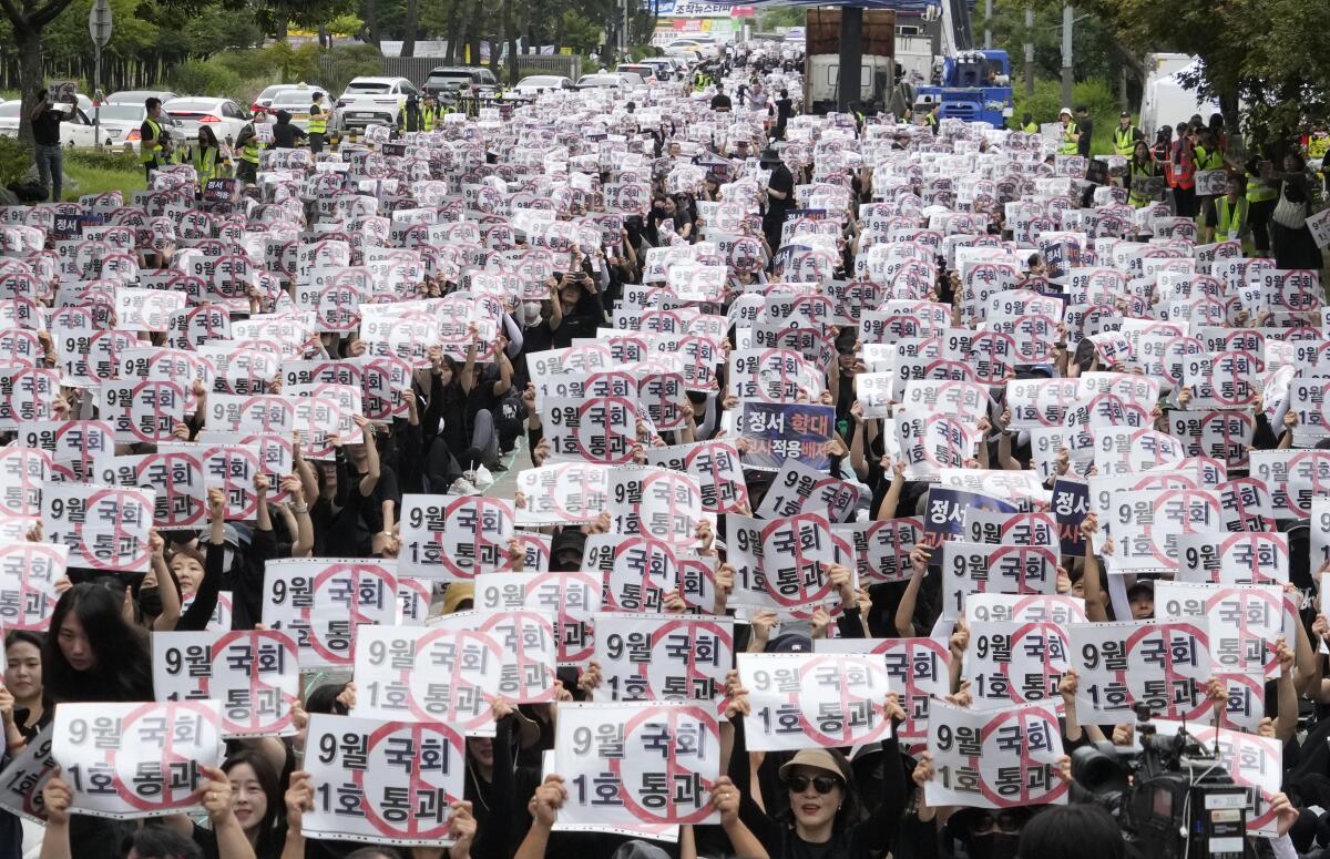 Profesores y personal de escuelas surcoreanas sostienen carteles durante una marcha 