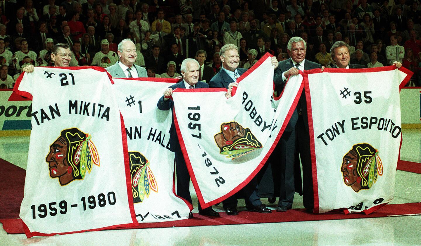 Former Blackhawks players pose with their retired jersey numbers on banners during a ceremony at the old Chicago Stadium before the start of the last regular season Hawks game there in 1994. Stan Mikita, from left, Glenn Hall, former GM Tommy Ivan, Bobby Hull, Hawks owner Bill Wirtz and Tony Esposito.