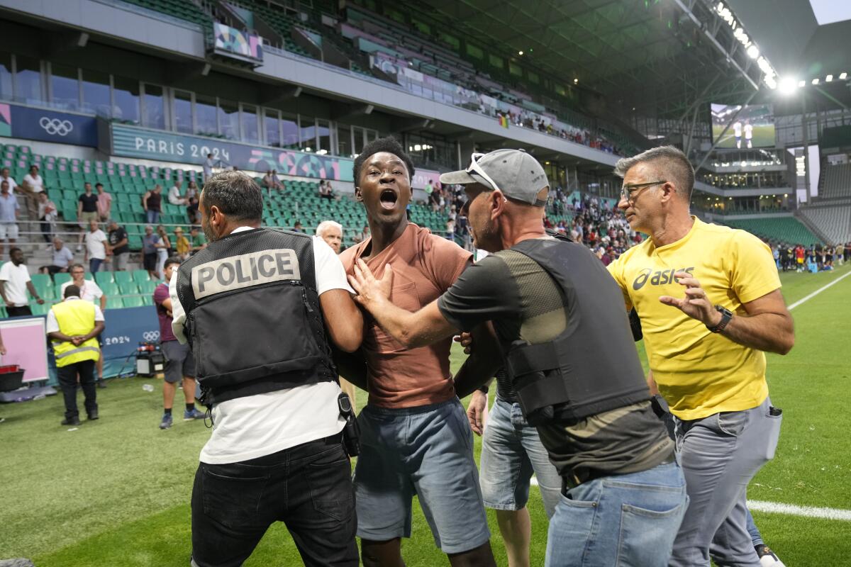 Security guards grab a pitch invader during the men's group stage soccer match between the U.S. and Guinea 