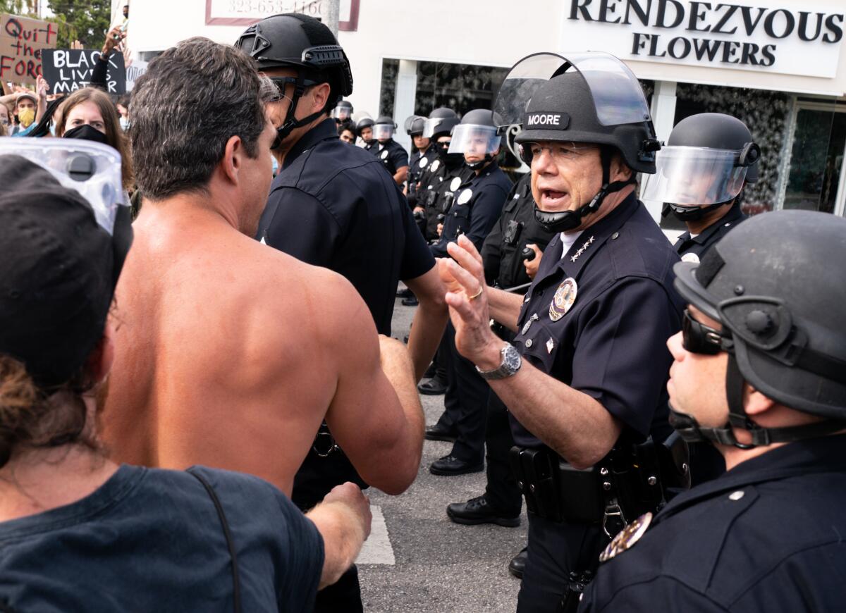 Chief Michel Moore, standing in a line of LAPD officers, speaks to protesters