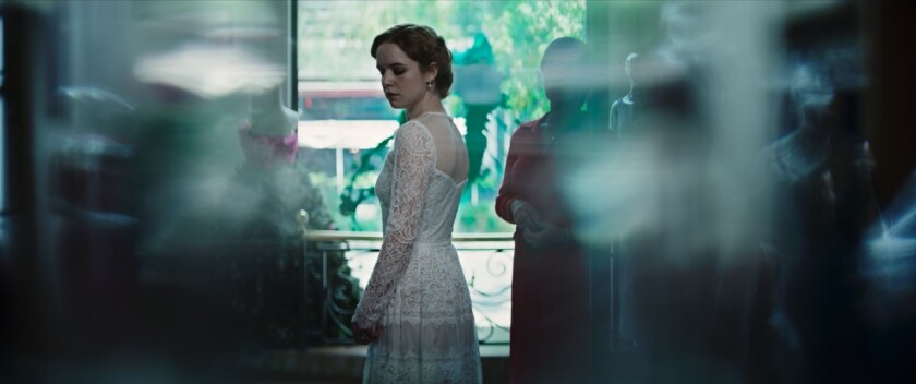 A woman in a white lace wedding dress is dimly seen in a shop.