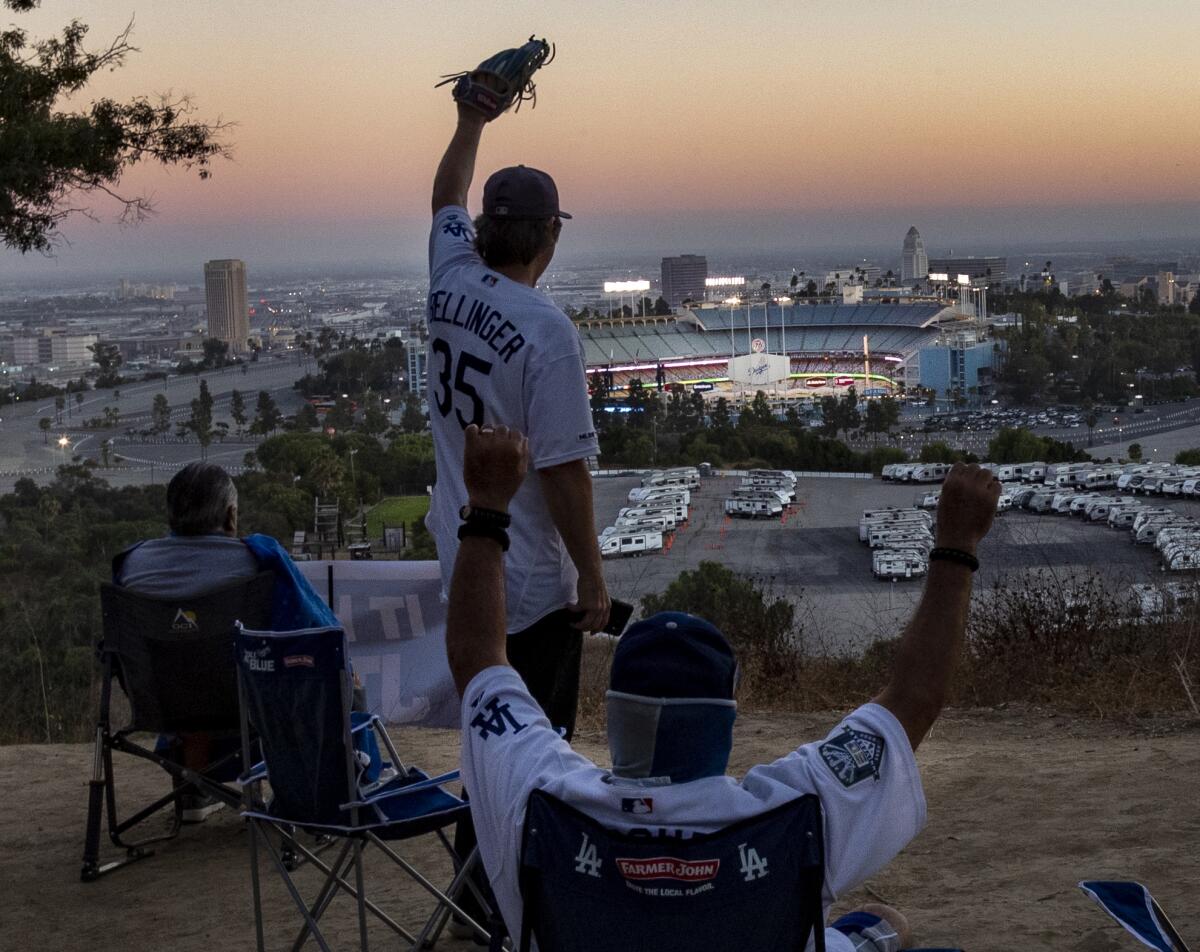 Fans sitting in Elysian Park with Dodger Stadium in the background.